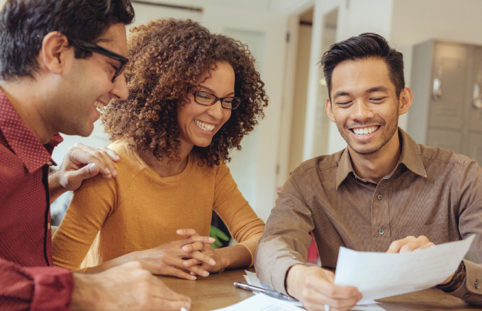 three smiling adults looking at a sheet of paper