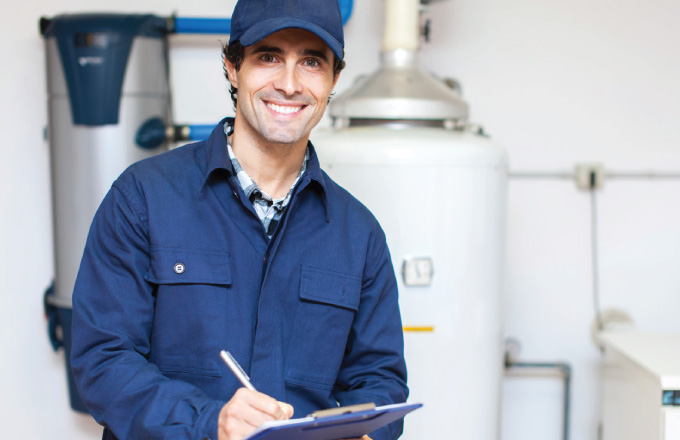 man smiling with clipboard in front of a water heater